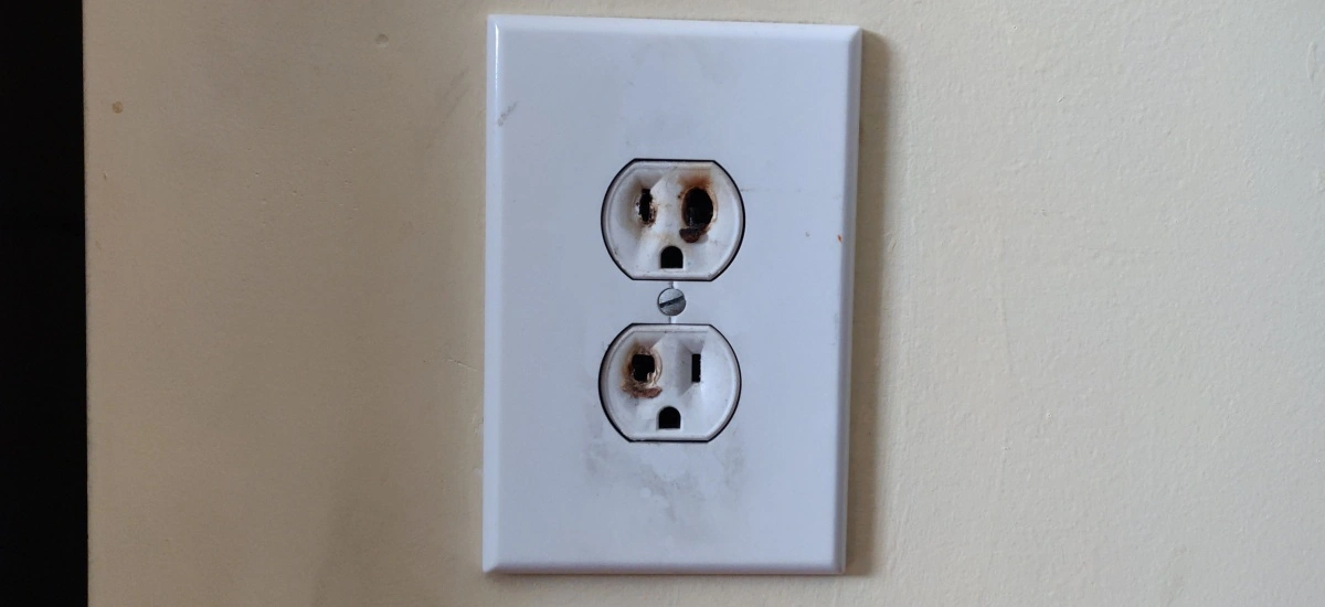 A white electrical outlet on a beige wall